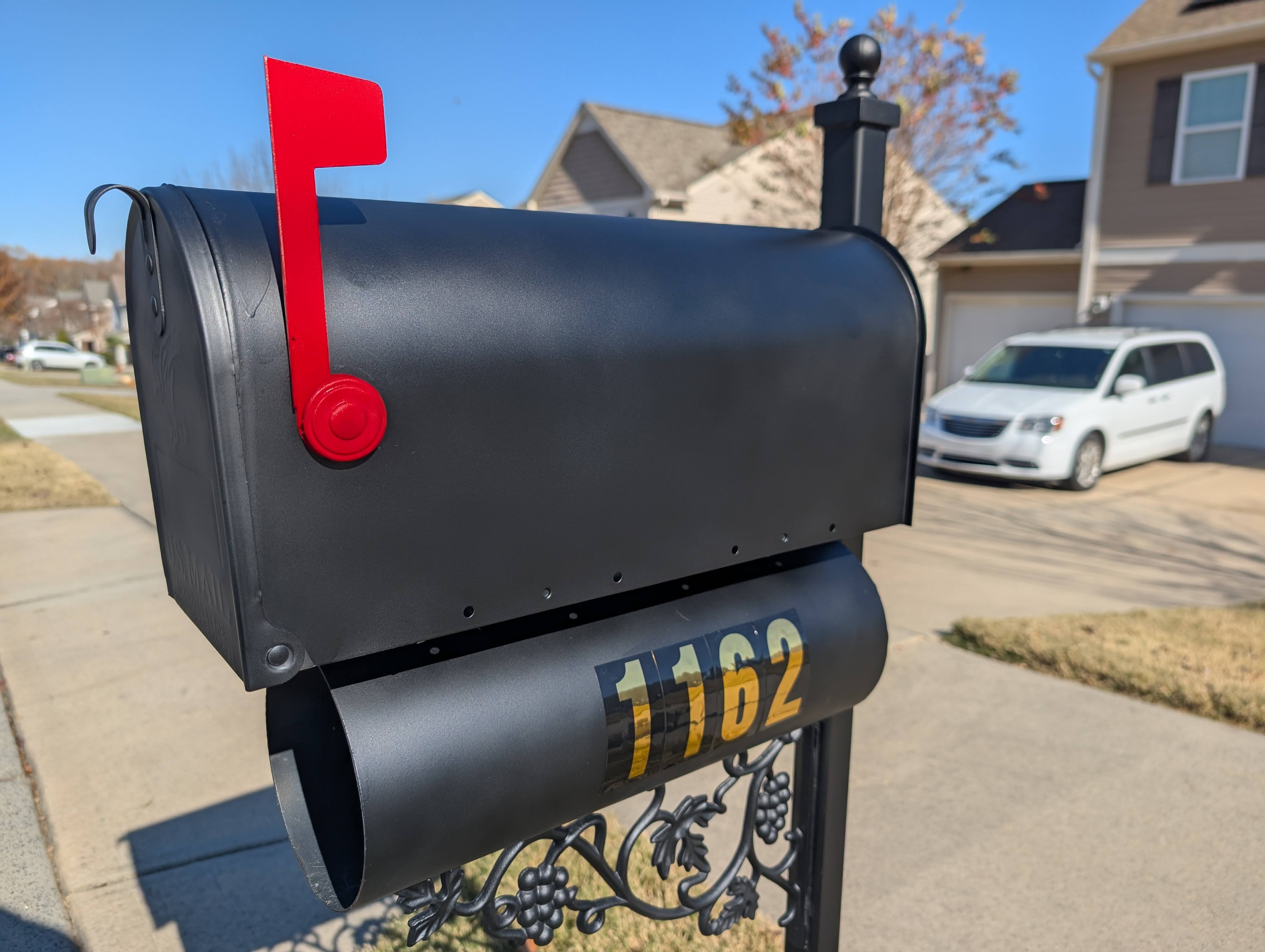 Newly installed black residential mailbox with bright red flag on freshly painted white post after professional installation in Indian Land SC